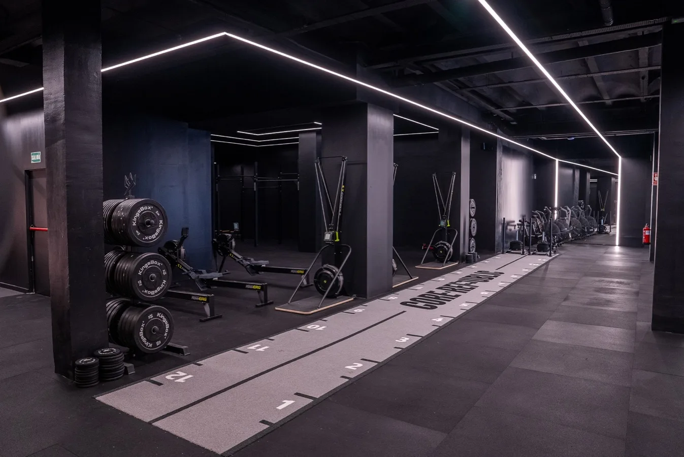 Zona d'entrenament amb rack de discos, mancuernes i pantalla del wod